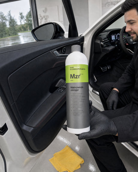Detergente multiuso Koch-Chemie Mzr in mano a Daniel davanti alla portiera aperta dell'Audi RS 5 bianca, pannello porta nero intenso.