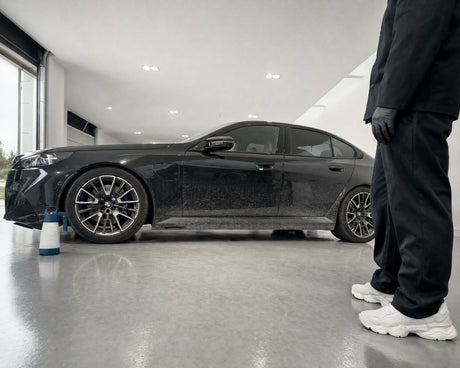Verschmutzte Flanke eines schwarzen BMW M5 in der Halle mit dem iK Sprayers "iK Foam" Pro 2 Alk Schaumsprüher (Alkalisch) 1.25 Liter daneben