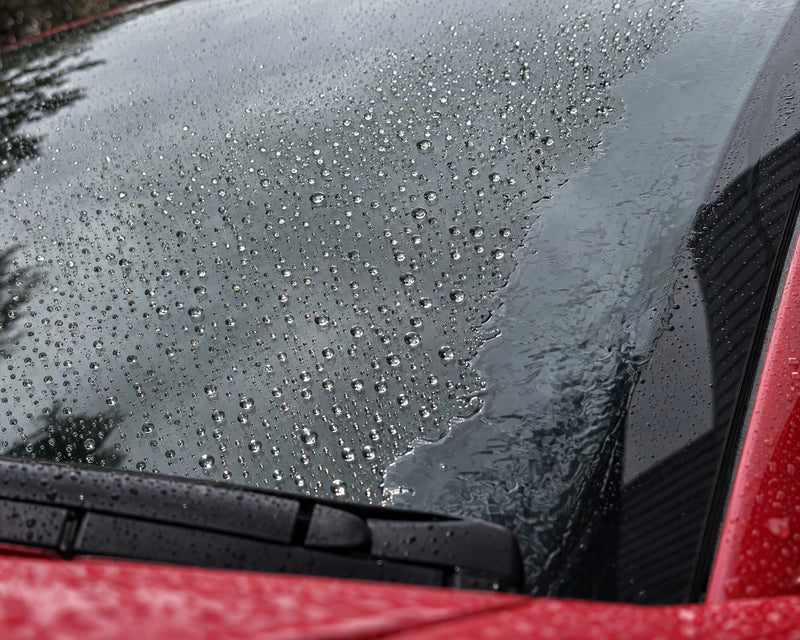 Antipioggia alla prova: gocce che perlano sul vetro sigillato, sul bordo non trattato resta un velo d'acqua