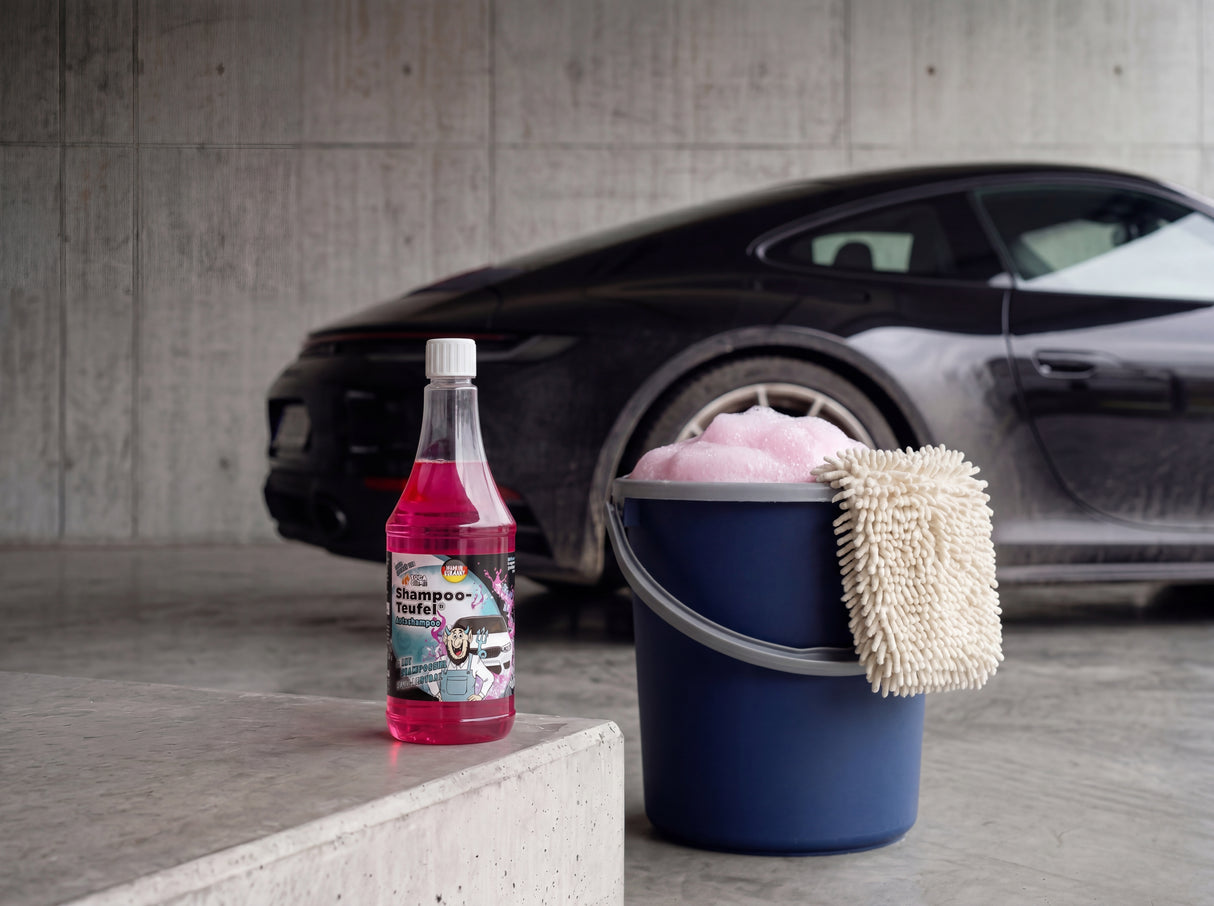 TUGA Chemie Shampoo-Teufel 1L Flasche mit blauem Detailing-Eimer und Waschhandschuh auf Betonvorplatz vor schwarzem Porsche 911