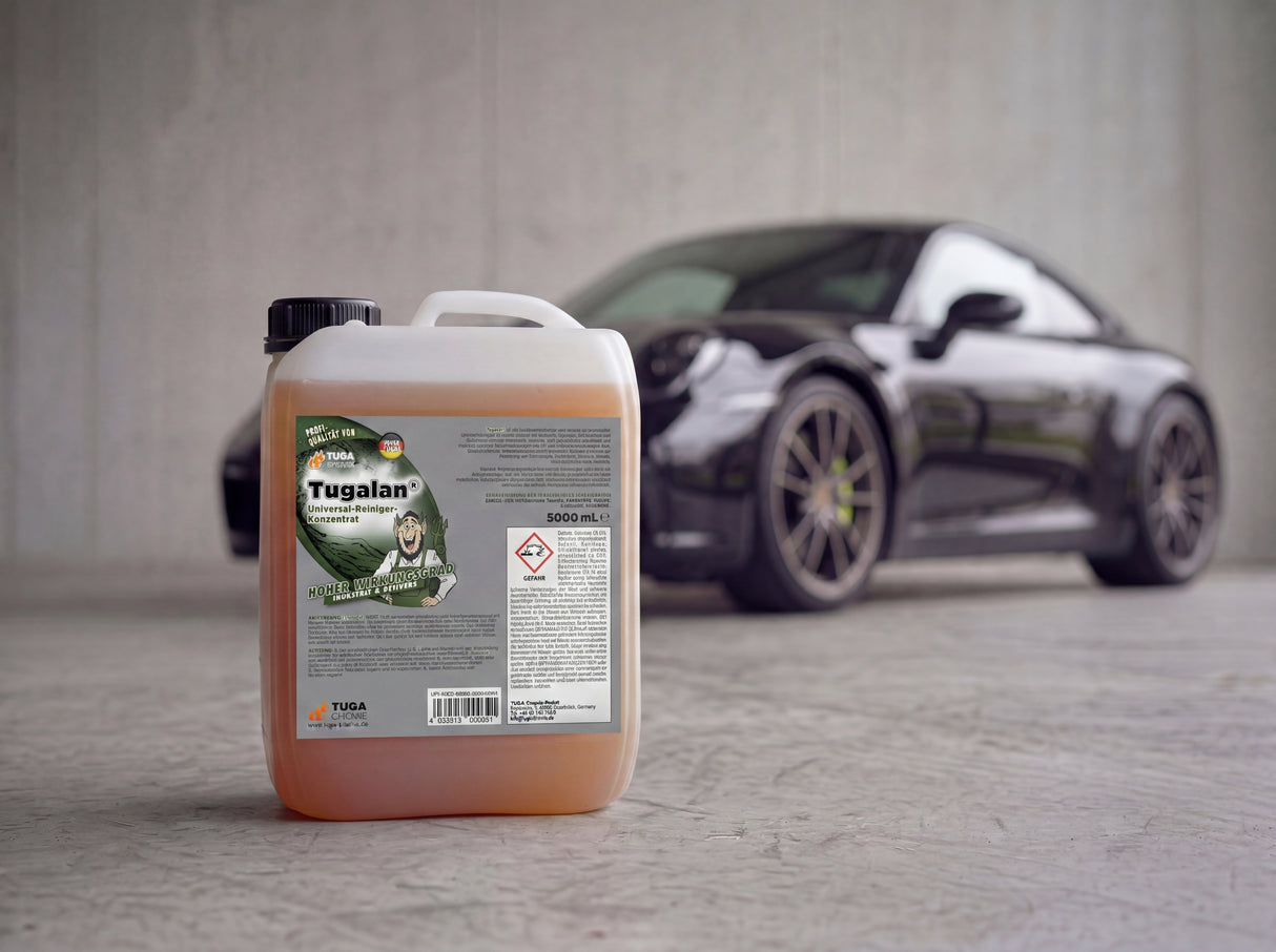 TUGA Chemie Tugalan 5 Liter Kanister mit amberfarbenem Konzentrat und grünem Label auf Betonvorplatz vor schwarzem Porsche 911